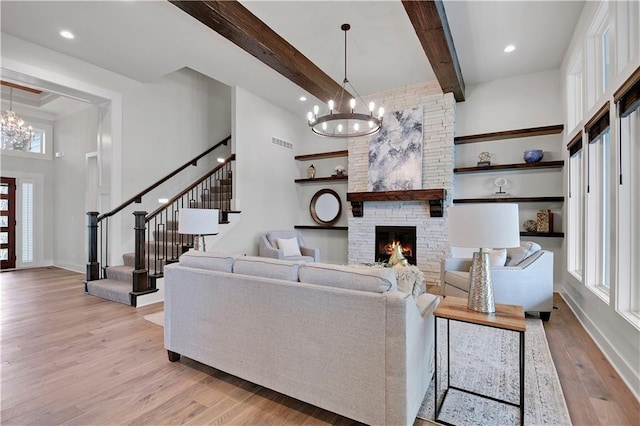 11212 W 170th Pl, Overland Park, KS 66221 - living area featuring a chandelier, light wood-style flooring, stairway, a stone fireplace, and beam ceiling