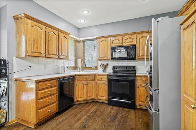 kitchen featuring light countertops, a sink, black appliances, and tasteful backsplash
