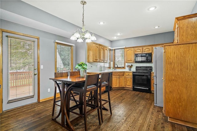 kitchen with dark wood-style flooring, black appliances, light countertops, a sink, and a notable chandelier