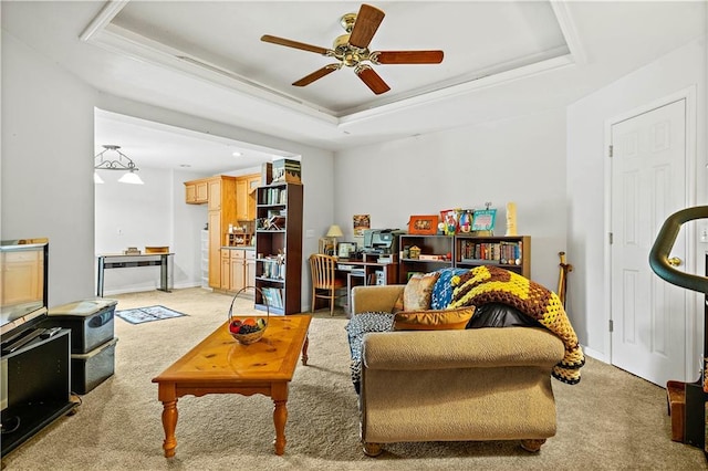 living room with baseboards, ceiling fan, a tray ceiling, and light colored carpet