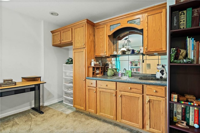 kitchen featuring brown cabinetry, a sink, open shelves, and dark countertops