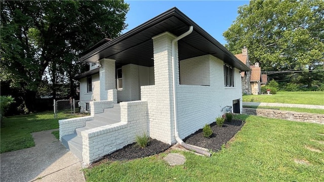 view of side of property with a lawn, a chimney, and brick siding