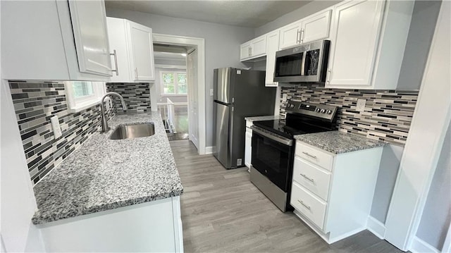 kitchen featuring a sink, appliances with stainless steel finishes, light stone countertops, and tasteful backsplash