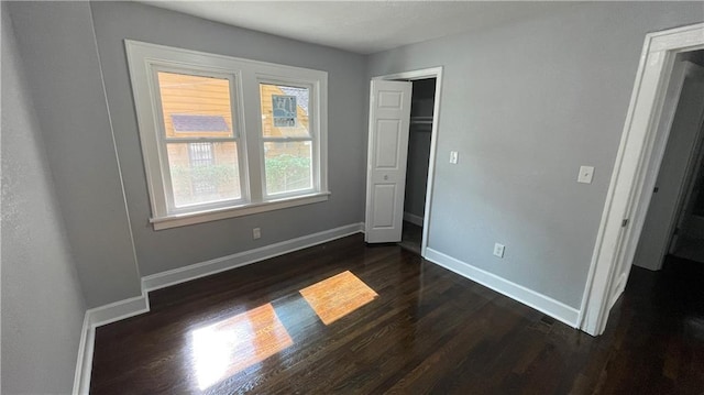 unfurnished bedroom featuring baseboards, a closet, and dark wood finished floors