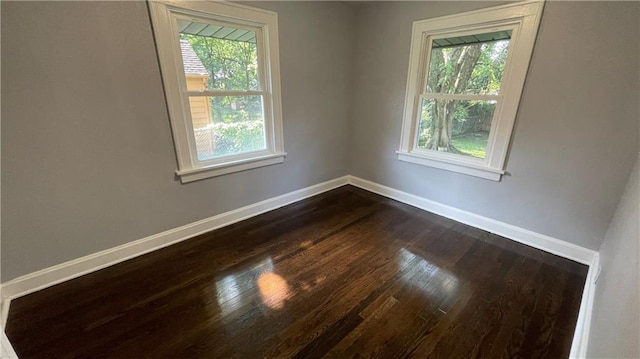 empty room featuring baseboards and dark wood-style floors