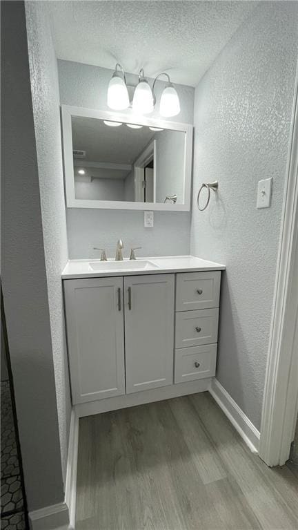 bathroom with vanity, a textured wall, and wood finished floors