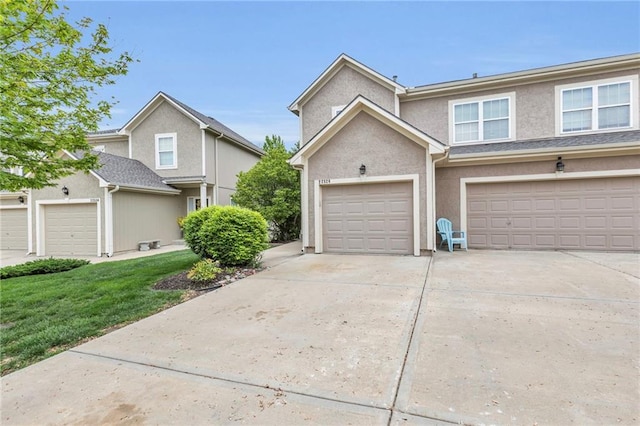 townhome / multi-family property with a front lawn, stucco siding, and driveway