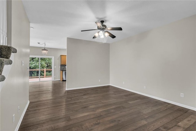 unfurnished room featuring baseboards, ceiling fan with notable chandelier, and dark wood-type flooring