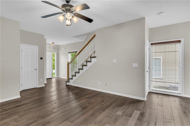 interior space with dark wood-type flooring, stairs, ceiling fan, and baseboards