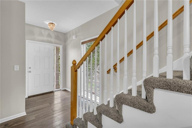 foyer entrance with baseboards, hardwood / wood-style floors, and stairway