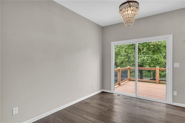 empty room with baseboards, visible vents, dark wood-type flooring, and a notable chandelier