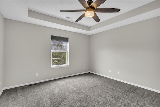 empty room with carpet flooring, baseboards, visible vents, and a tray ceiling