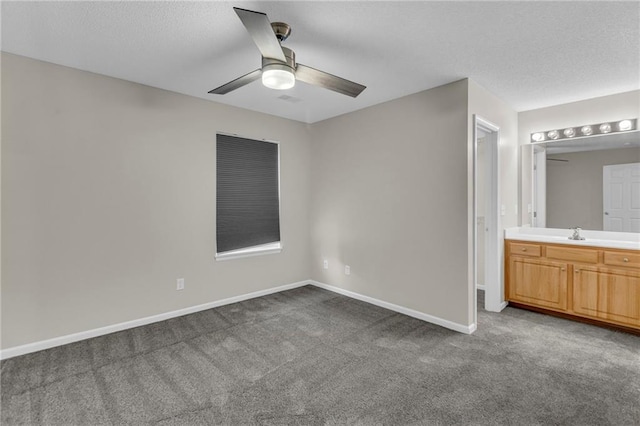 unfurnished bedroom featuring carpet floors, baseboards, a sink, and ensuite bathroom