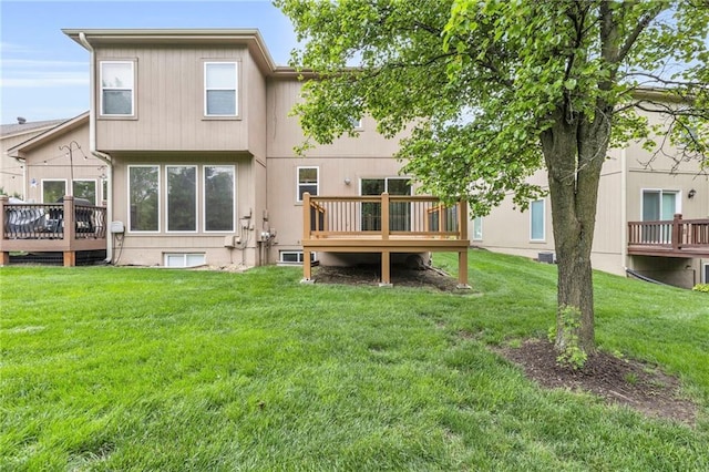 rear view of property featuring a lawn and a wooden deck