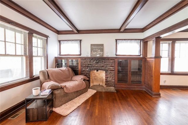 sitting room with a fireplace, hardwood / wood-style flooring, beam ceiling, and a wealth of natural light