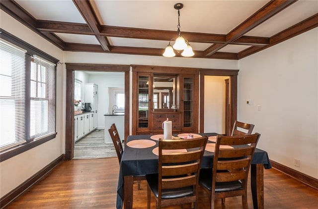 dining area with dark wood-type flooring, coffered ceiling, and beamed ceiling