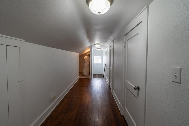 corridor with baseboards, vaulted ceiling, and dark wood-type flooring