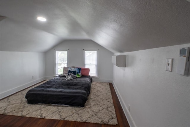 bedroom featuring baseboards, a textured ceiling, wood finished floors, and vaulted ceiling