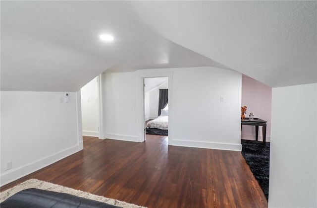 additional living space with baseboards, vaulted ceiling, and wood finished floors