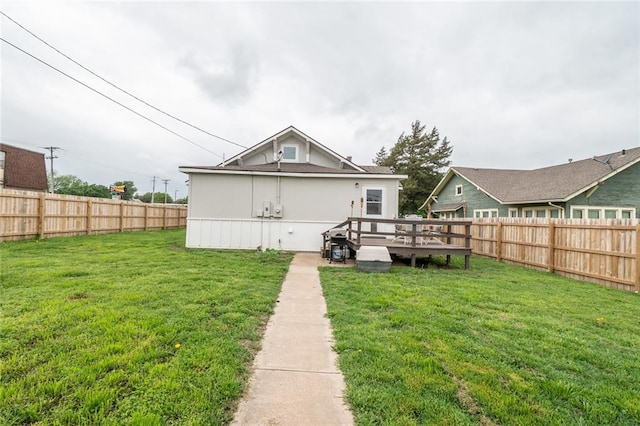 rear view of house with a lawn, a deck, and a fenced backyard