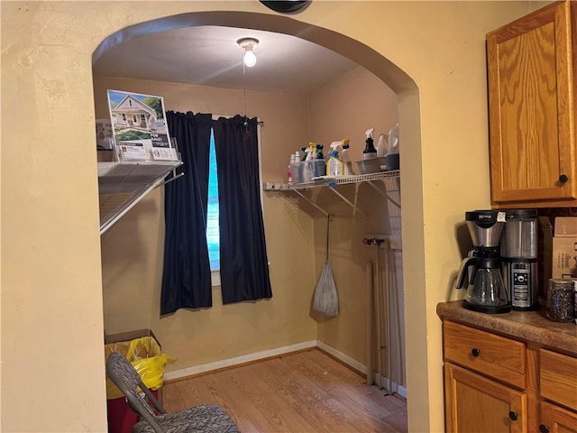 spacious closet with wood finished floors and arched walkways