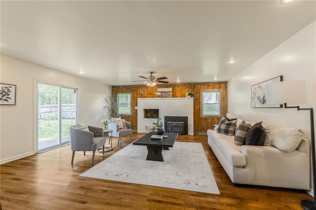 living area with a brick fireplace, recessed lighting, wood walls, and dark wood-style floors