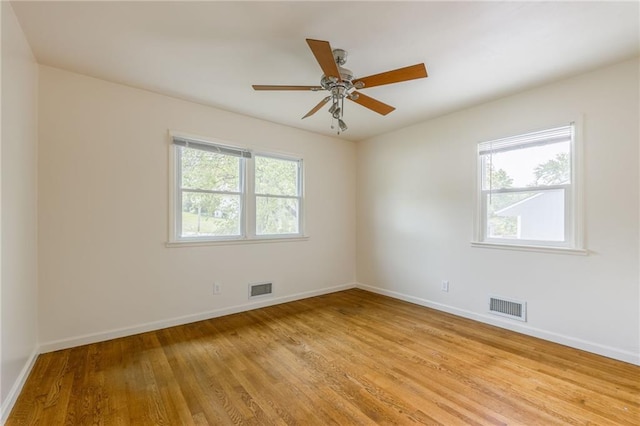 spare room with light wood-style floors, baseboards, a ceiling fan, and visible vents