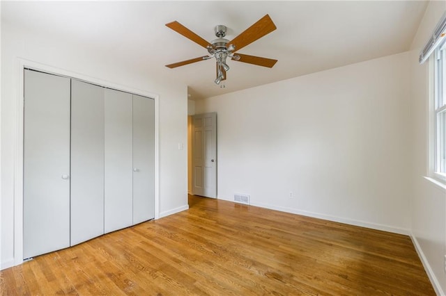 unfurnished bedroom featuring baseboards, visible vents, light wood finished floors, and a closet