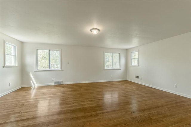 empty room with baseboards, wood finished floors, and visible vents