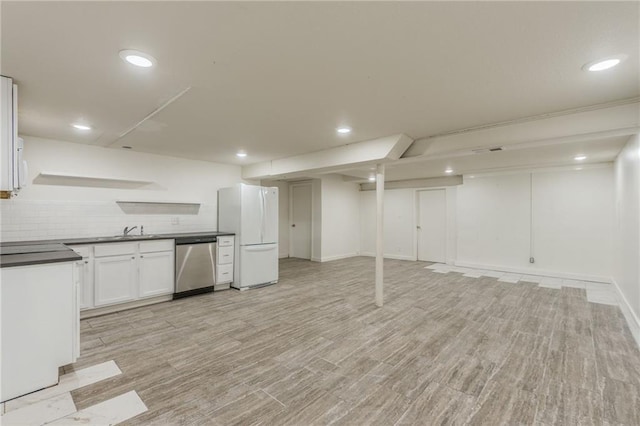 finished below grade area with a sink, light wood-style flooring, freestanding refrigerator, recessed lighting, and baseboards