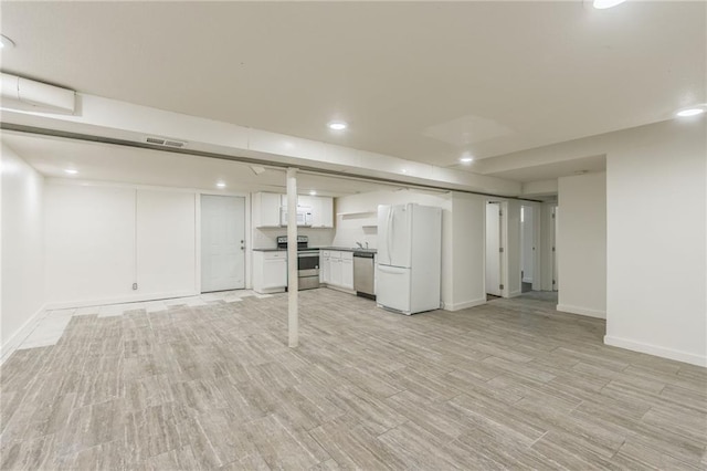 finished below grade area featuring visible vents, freestanding refrigerator, baseboards, and recessed lighting