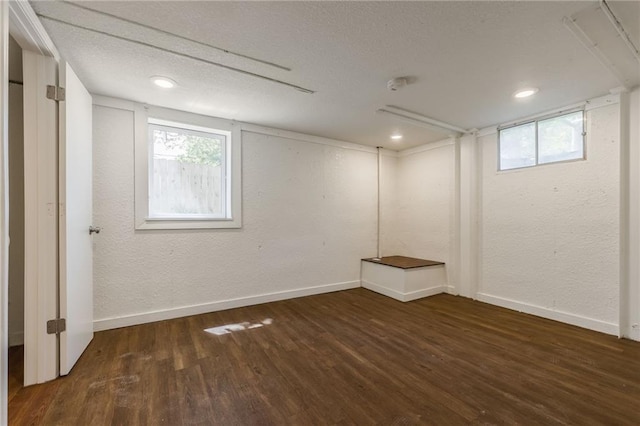 below grade area with baseboards, a textured wall, and wood finished floors