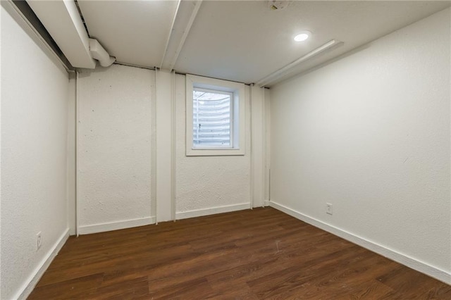 below grade area featuring baseboards, a textured wall, and wood finished floors