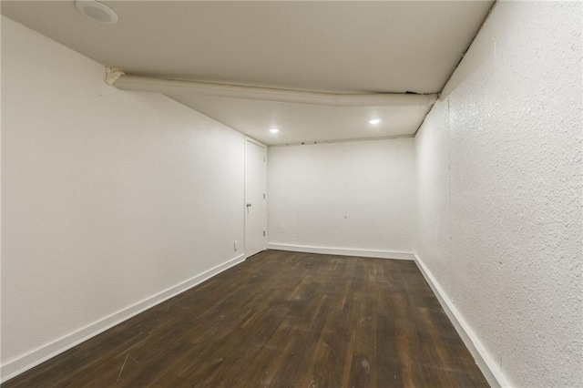 interior space featuring baseboards, a textured wall, and wood finished floors