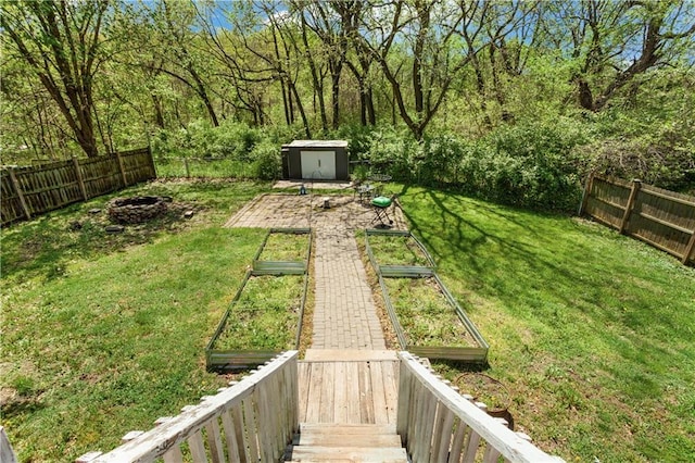 view of yard featuring an outdoor structure, a vegetable garden, a fenced backyard, and a storage unit