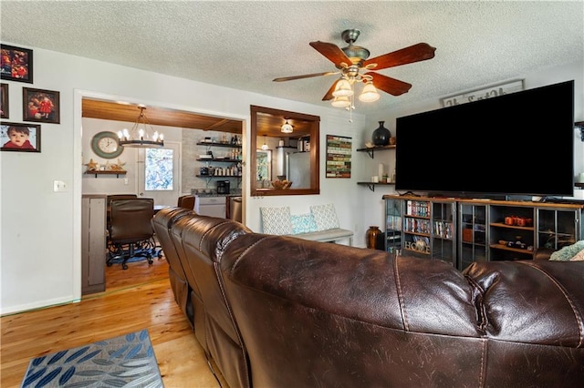 living area featuring a textured ceiling, ceiling fan with notable chandelier, and wood finished floors