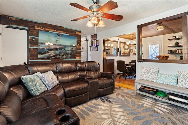 living area featuring a textured ceiling, ceiling fan with notable chandelier, and wood finished floors