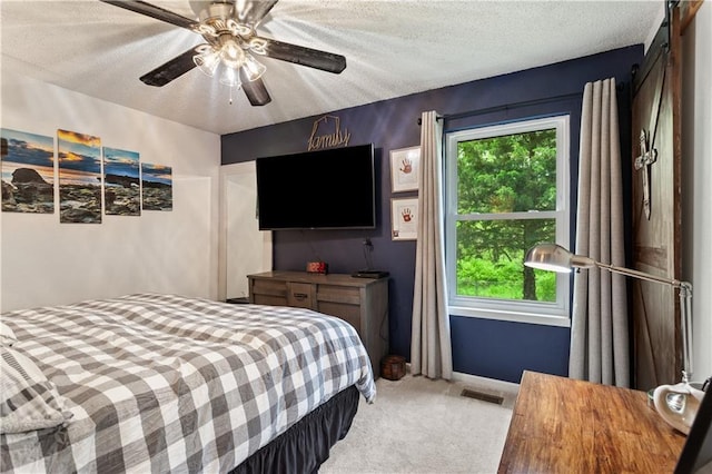 carpeted bedroom featuring a ceiling fan, a textured ceiling, visible vents, and baseboards