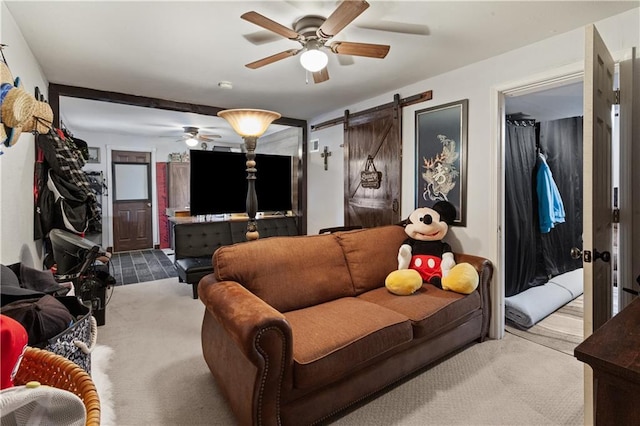 living area with carpet floors, a ceiling fan, and a barn door