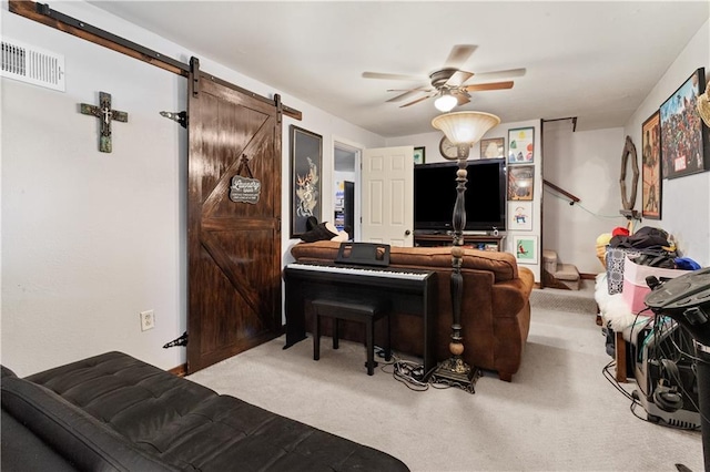 living room featuring ceiling fan, visible vents, a barn door, and carpet