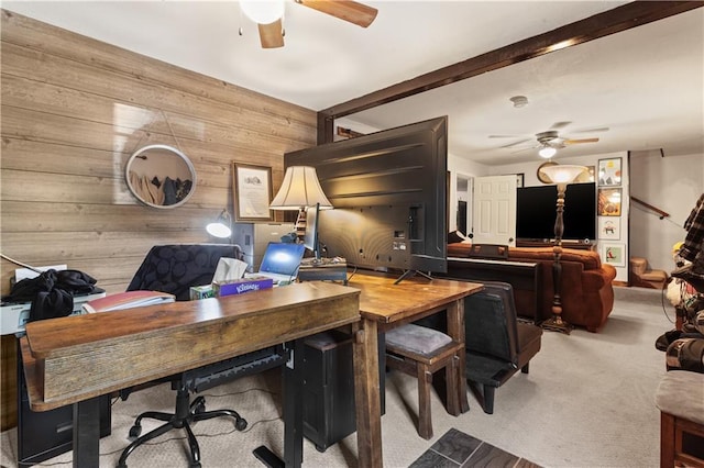 carpeted office featuring wooden walls and a ceiling fan
