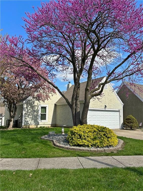 9629 N Locust Dr, Kansas City, MO 64155 - view of side of property with an attached garage, concrete driveway, a yard, and stucco siding