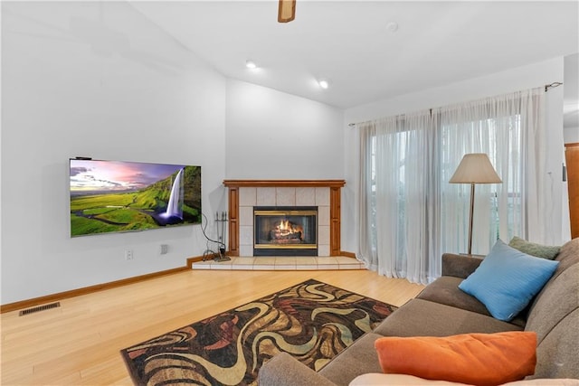 9629 N Locust Dr, Kansas City, MO 64155 - living room with visible vents, wood finished floors, baseboards, a tiled fireplace, and vaulted ceiling
