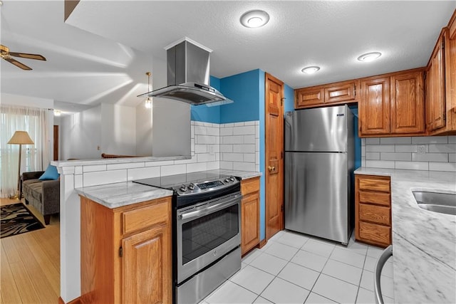 9629 N Locust Dr, Kansas City, MO 64155 - kitchen with brown cabinetry, open floor plan, ceiling fan, island exhaust hood, and appliances with stainless steel finishes