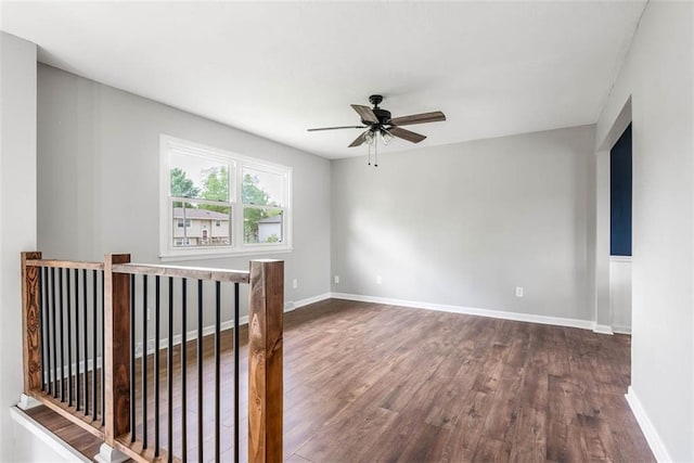 spare room featuring dark wood-style flooring, ceiling fan, and baseboards
