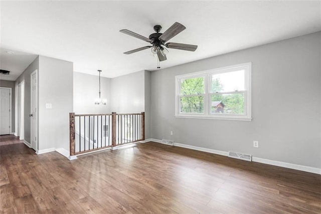 unfurnished room featuring a chandelier, wood finished floors, ceiling fan, and baseboards