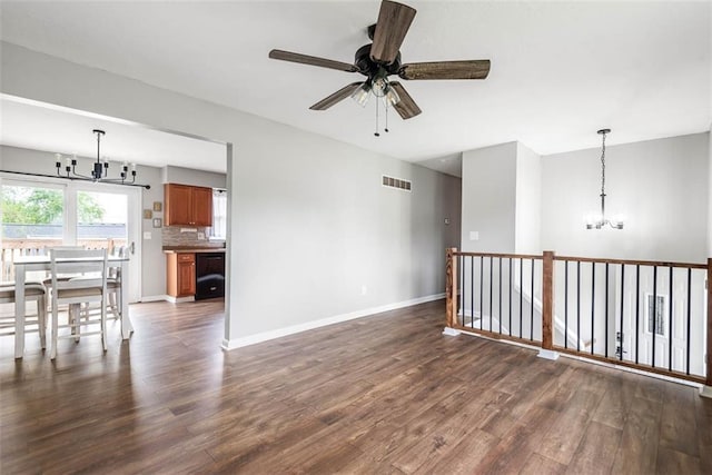 unfurnished room featuring a chandelier, dark wood-type flooring, ceiling fan, and baseboards