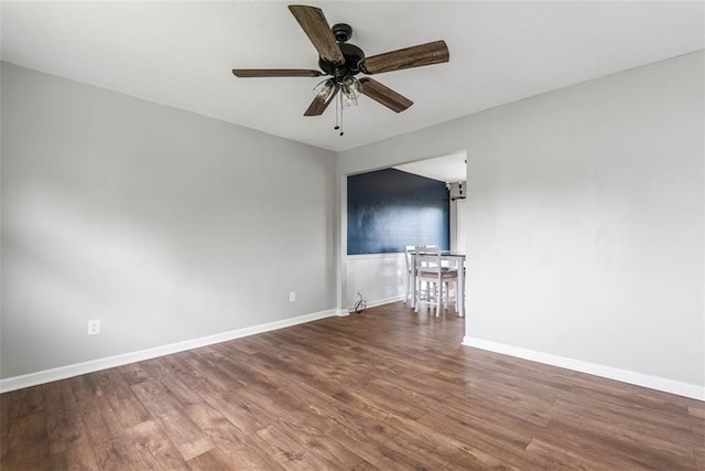 empty room featuring a ceiling fan, wood finished floors, and baseboards