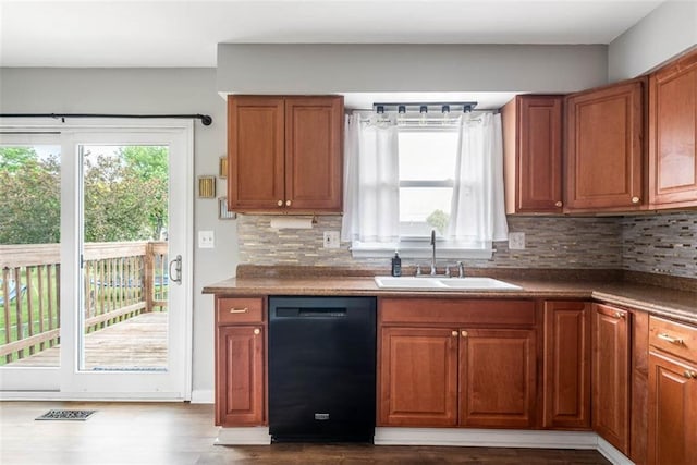 kitchen featuring black dishwasher, a sink, brown cabinetry, and backsplash