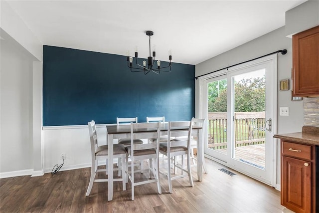 dining area with a chandelier, wood finished floors, and baseboards